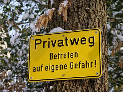 Schilder mit der Aufschrift: Privatweg - Betreten auf eigene Gefahr!