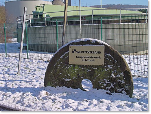 Schleifstein mit einem Messingschild, Aufschrift: Wupperverband :: Gruppenklärwerk Kohlfurth
