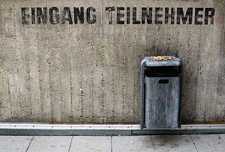 Foto: Mauer mit Schrift und bekipptem Mülleimer